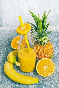 黄色水果冰沙瓶与饮用吸管新鲜成分香蕉,橘子菠萝,正观看,图片