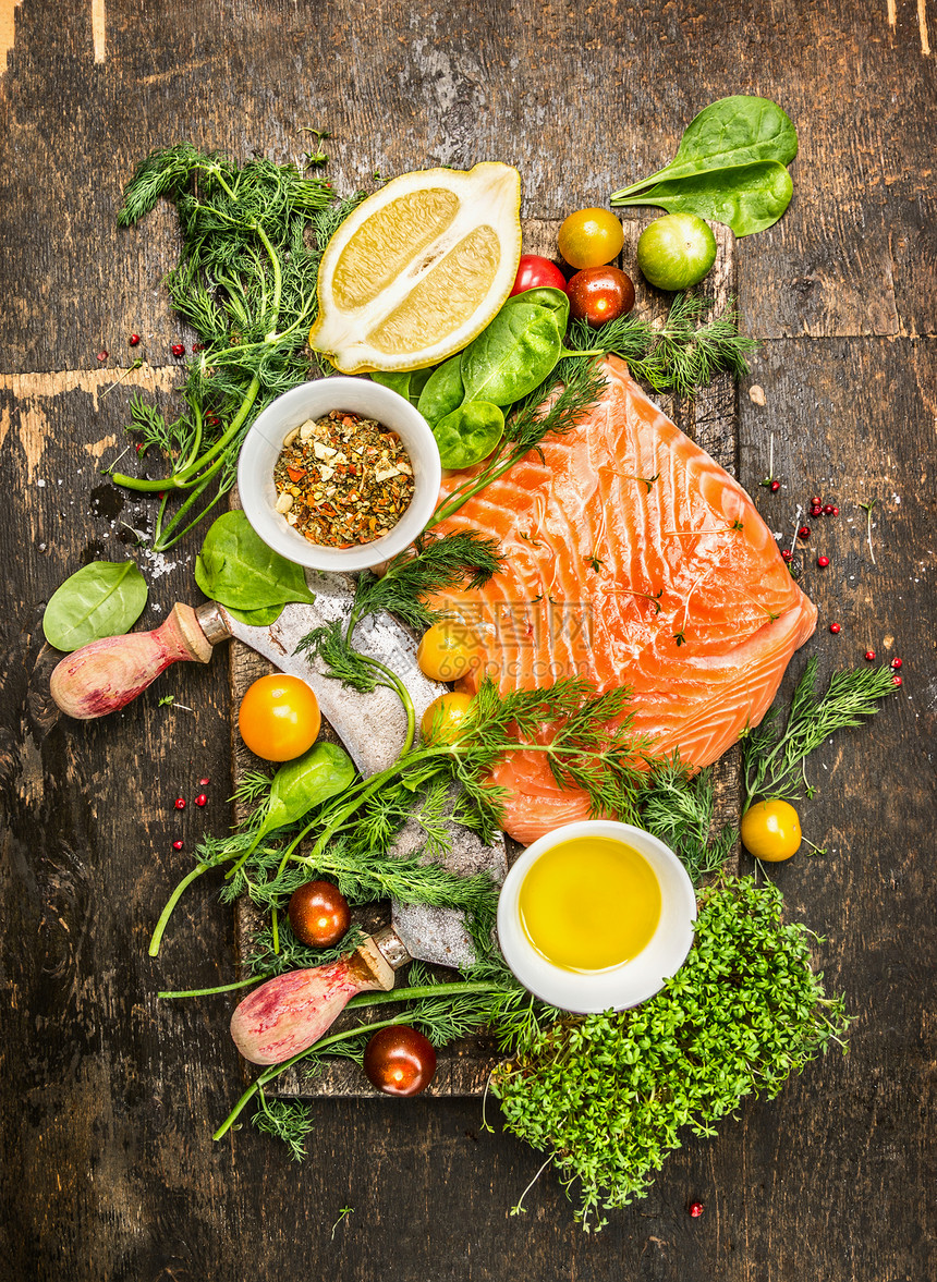 生鲑鱼片与新鲜健康的草药,蔬菜,油香料乡村木制背景,顶部视图图片