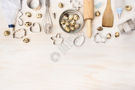 复活节烘焙工具与鹌鹑蛋饼干切割机白色木制背景,顶部视图,文字的地方图片