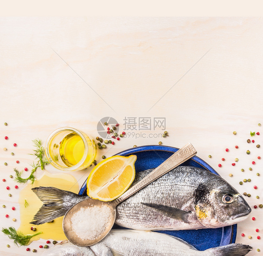 生多拉多鱼与香料,柠檬,油盐蓝色盘子白色的木制背景,顶部视图图片