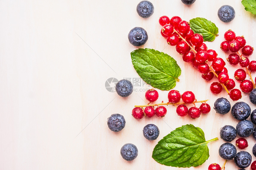 红色醋栗,蓝莓黑莓与水滴薄荷叶白色木制背景,顶部视图,文字的地方图片