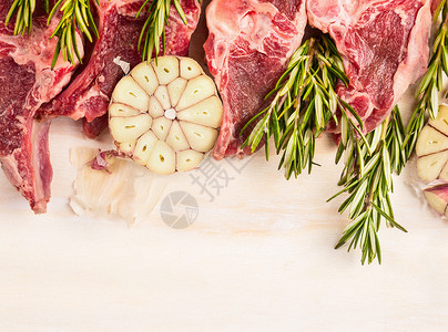 生羊肉与大蒜迷迭香白色木制背,顶部视图,边界图片