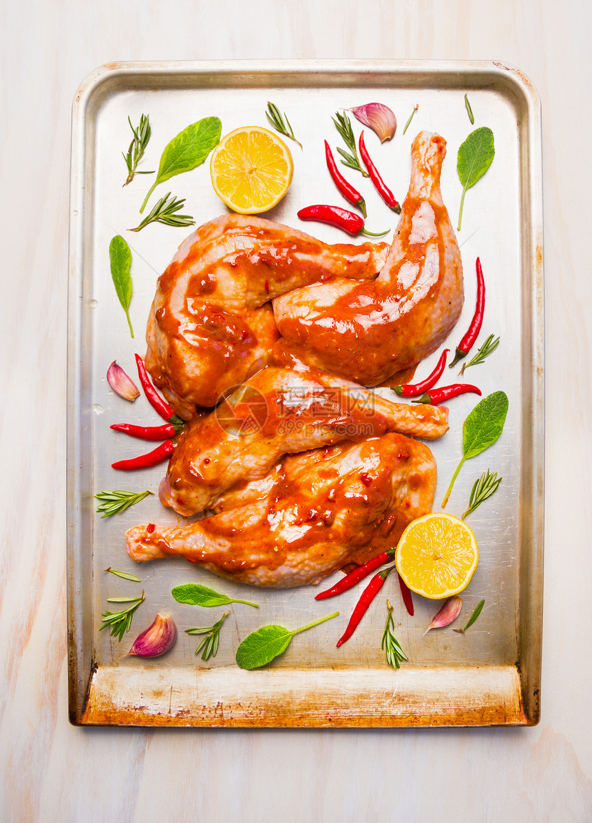 生鸡腿与红辣酱,鼠尾草柠檬烘焙托盘白色木制背景,顶部的图片