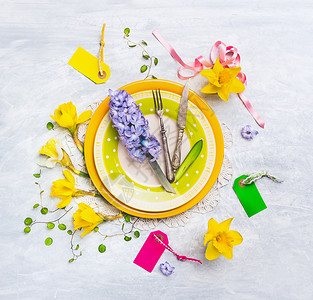 春季餐桌装饰用水仙花,风信子,标志,丝带,刀叉绿色盘子上,顶部观看图片
