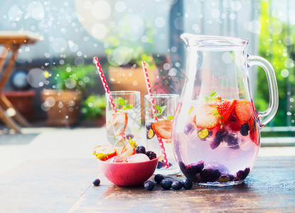 水壶杯子与浆果注入水桌子上的花园,正视图图片