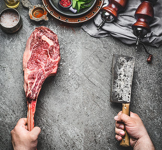 屠夫厨师的手着战斧牛肉牛排切肉刀黑暗的乡村厨房桌子背景与烹饪原料调味品,顶部视图,文字的地方背景图片
