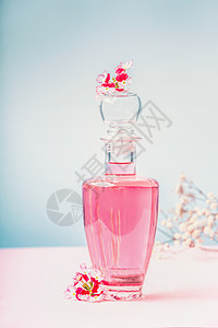 瓶带粉红色花朵的乳液香水,天然化妆品美容,背景为淡蓝色,正图片