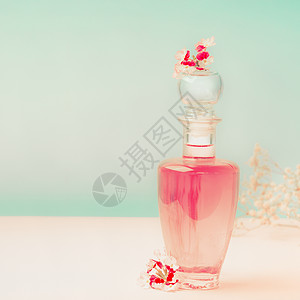 粉红色化妆品瓶与护肤品香水与花站桌子上的绿松石背景,正视图美丽的图片