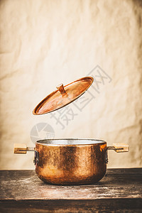 铜锅与飞开盖子木制厨房桌子墙壁背景,正视图图片