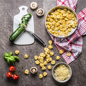 托特里尼与西葫芦素食烹饪原料厨房桌子背景与切割板刀,顶部视图健康的烹饪饮食意大利食品图片