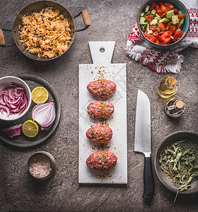 餐桌背景上白色切割板上的生肉球,刀饭锅沙拉菜烹饪准备顶部视图健康干净的食物饮食观念背景