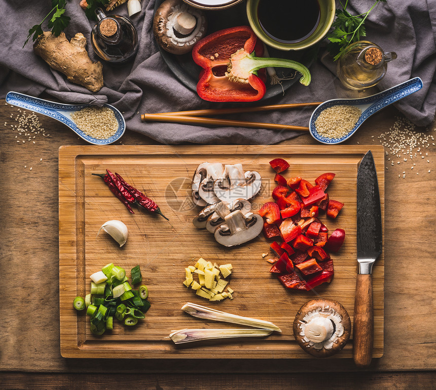 切碎的蔬菜,用于炒菜,厨房桌子背景上的木制切割板上,带配料,顶部视图亚洲食物饮食,中国泰国菜的图片