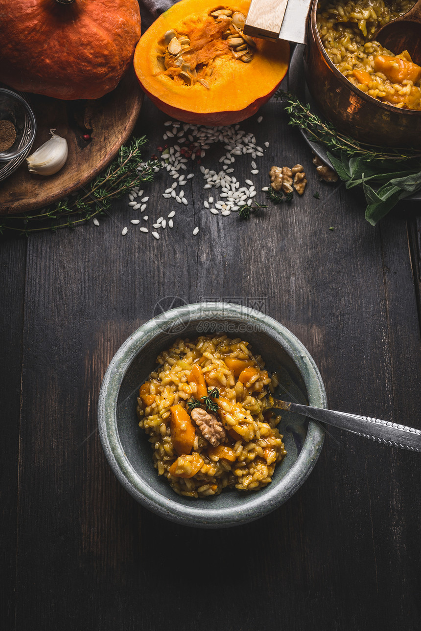 碗与素食南瓜烩饭勺子黑暗的乡村厨房桌子背景与烹饪配料,顶部视图健康干净的季节食物饮食观念图片