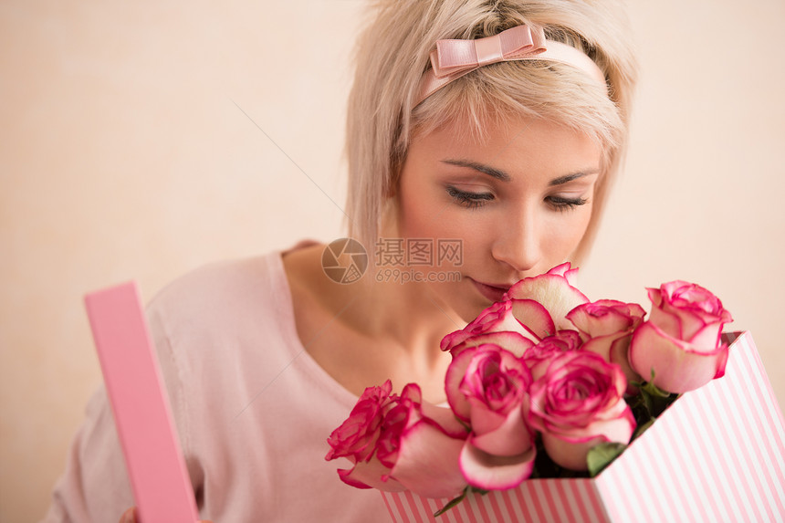 轻漂亮的女人着蝴蝶结,粉红色的玫瑰她很满意情人节国际妇女节庆祝活动图片
