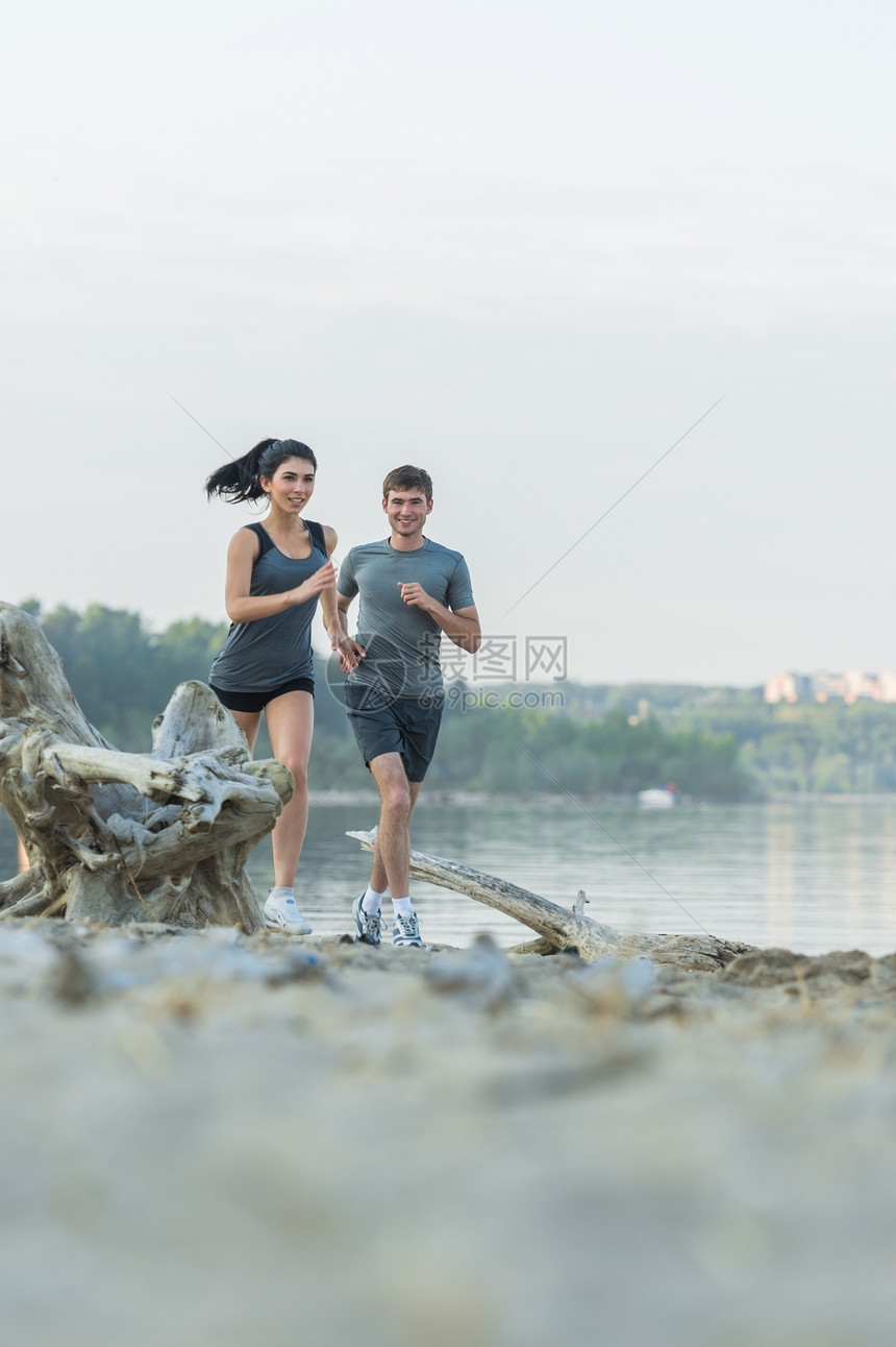 欢快的西牙白人夫妇早上海滩上跑步图片