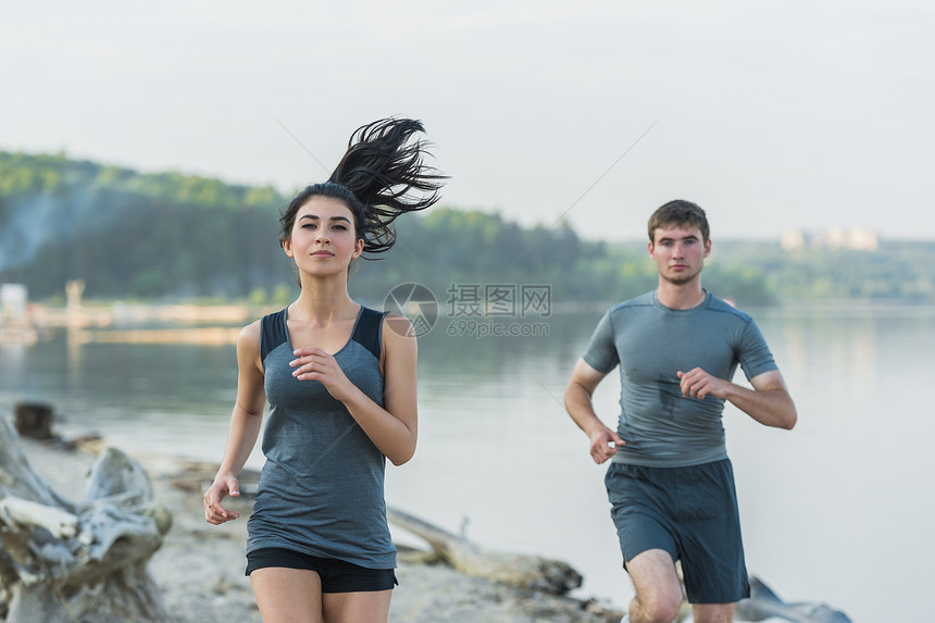 欢快的西牙白人夫妇早上海滩上跑步图片