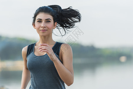 轻的女士早上海滩上跑步高清图片