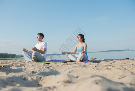 放松的救济轻夫妇早上海滩上瑜伽冥想背景