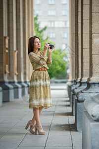 快乐的旅行者女孩城市街道上用复古相机拍摄历史建筑的照片图片