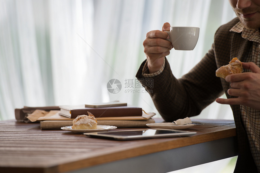 轻的商人喝咖啡休息用平板电脑图片