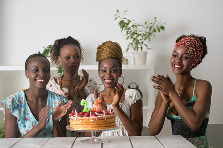 快乐的非洲女孩的肖像,看着生日蛋糕,周围都聚会上的朋友图片