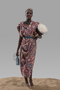 吸引力的轻非洲妇女着传统的鼓水壶灰色的工作室背景上的沙子图片