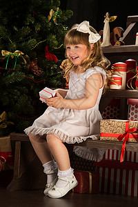 快乐的小女孩着诞礼物坐诞树附近图片