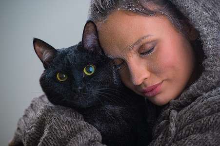 抱着大黑猫的轻善良女人的冬天肖像霜雪他们身上背景图片