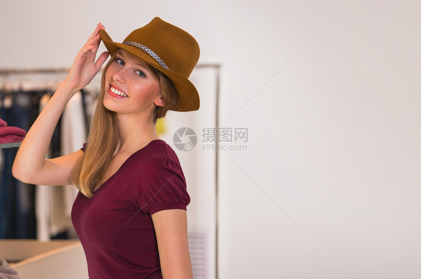 美女穿着棕色帽子服装店购物,看着相机图片
