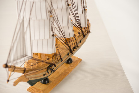 白色背景下白色桌子上的木船玩具模型背景图片