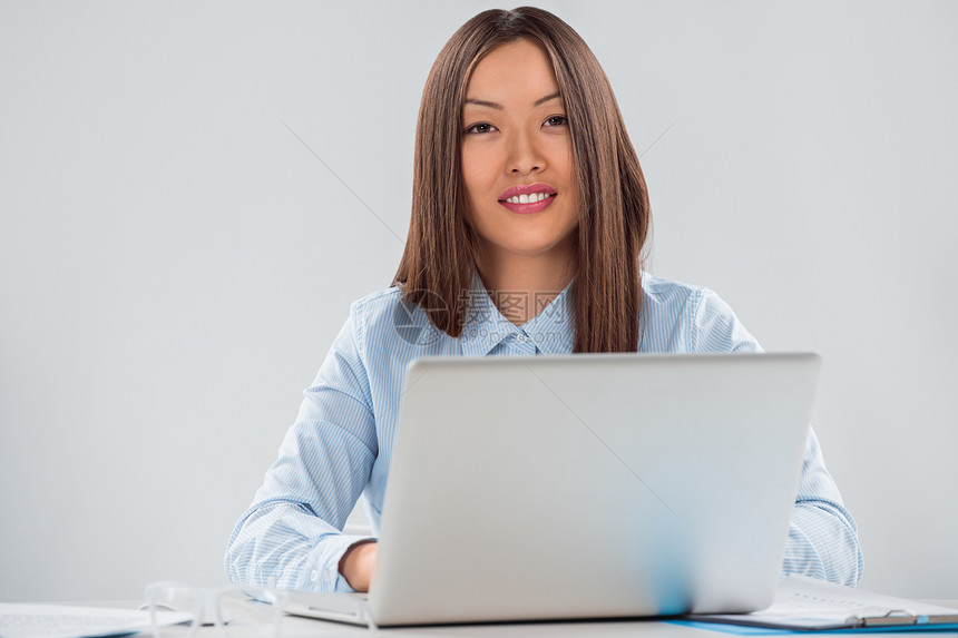 位快乐的轻女商业高管办公室里用笔记本电脑工作的肖像图片