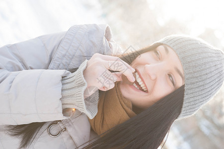 打昏穿着冬装的轻女人吃着阳光照亮的饼干背景