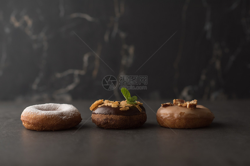 三个甜甜圈黑暗的石头背景上图片