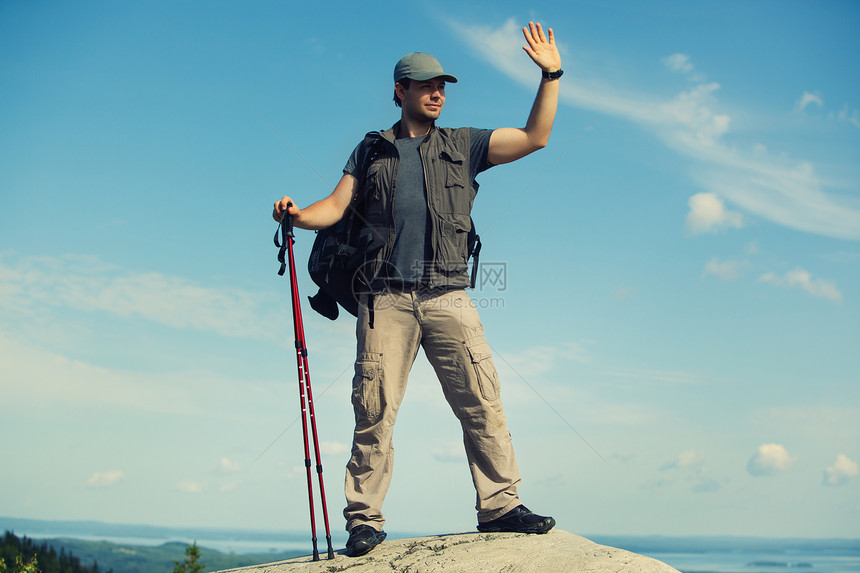 轻人游客,背包棍子站山顶上挥舞着手图片