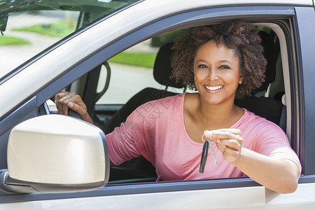 美丽的轻混血黑人非裔美国妇女开着辆车,着钥匙图片