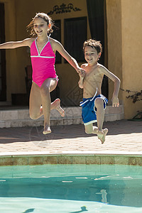两个男孩女孩笑着玩着跳进游泳池图片