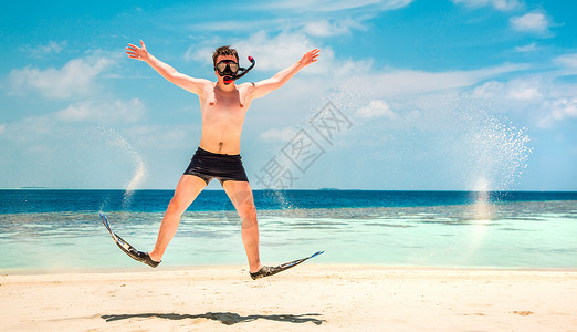 趣的人跳着脚蹼具马尔代夫群岛的热带海滩度假背景图片