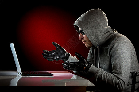 强盗黑客戴着带笔记本电脑的太阳镜设计图片