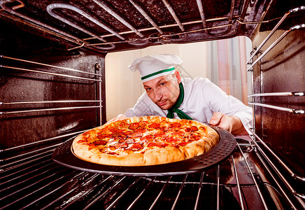 厨师烤箱里准备意大利辣香肠披萨,烤箱看烤箱里饭图片