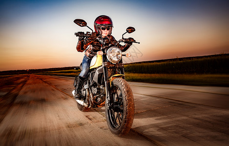 骑摩托车的骑自行车的女孩穿着皮夹克头盔背景图片