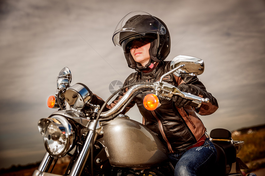 骑摩托车的骑自行车的女孩穿着皮夹克头盔图片