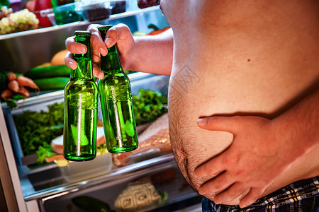 胖子手里着啤酒冰箱旁边高清图片
