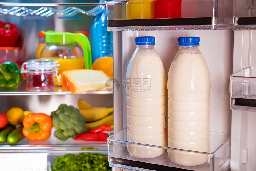 打开装满食物的冰箱把注意力集中冰箱里的牛奶瓶上图片