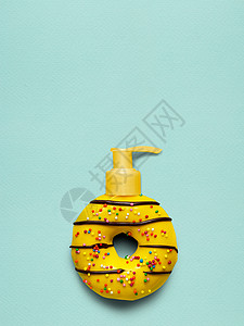创造的静物生活,个美味的甜黄甜甜圈与化妆品泵分配器蓝色背景图片