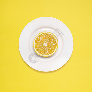 黄色背景的白色盘子上的柠檬片图片