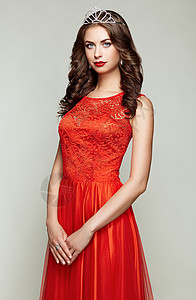 穿着优雅红色连衣裙的美丽女人的时尚肖像着优雅发型珠宝的女孩图片