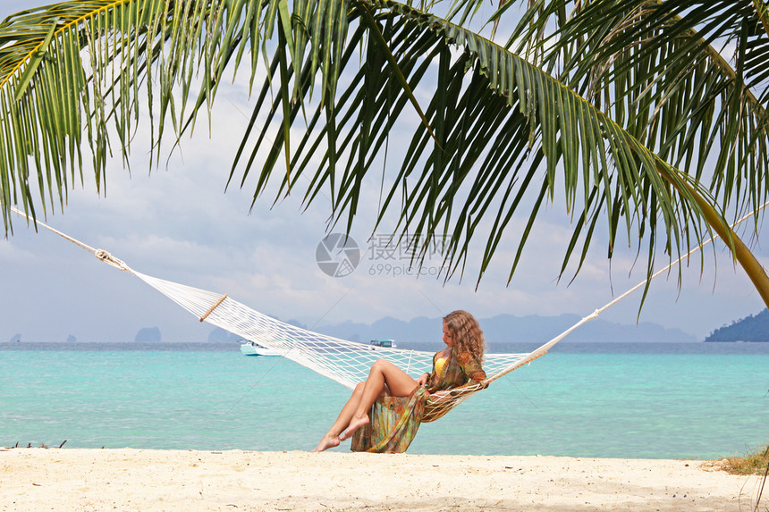 热带海滩上的女人美丽的轻女人穿着比基尼热带海滩的吊床上图片