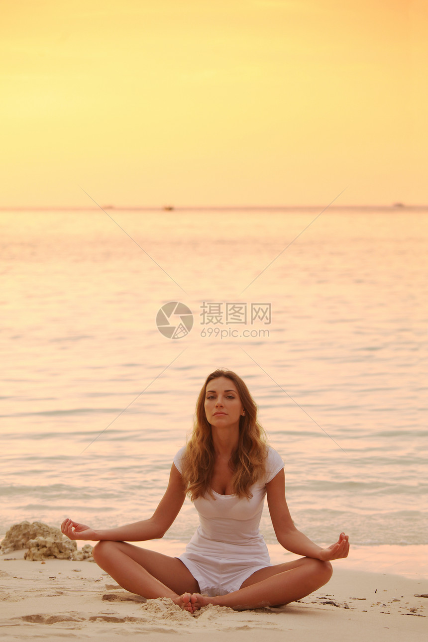 日落时瑜伽海滩上日落时,穿着莲花瑜伽姿势的女人图片