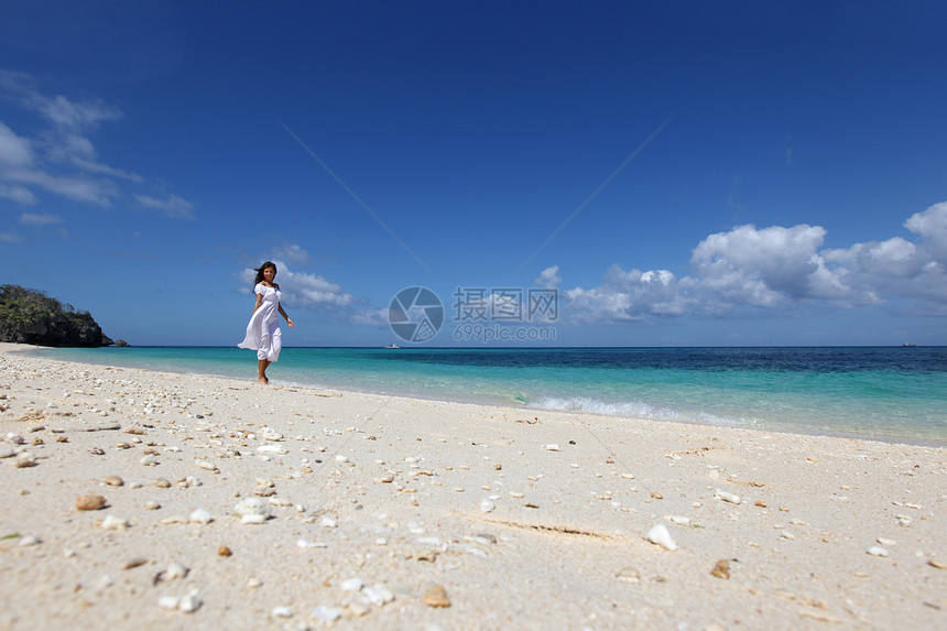 海滩上穿裙子的女人穿着白色连衣裙海滩上散步的漂亮轻女人图片