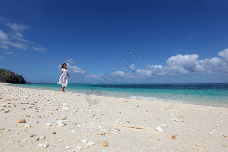 海滩上穿裙子的女人穿着白色连衣裙海滩上散步的漂亮轻女人图片